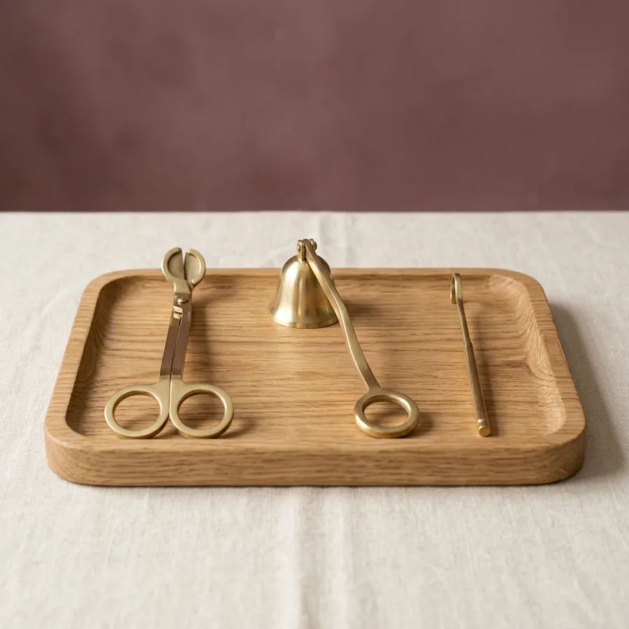 Brass candle care kit on a wooden tray